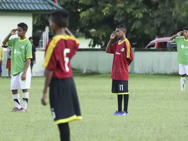 Para pemain SSB Maehanu dan SSB Persenal hormat bendera pada Liga Remaja UC News di Lapangan Masariku Yonif 733, Ambon, Selasa (28/11/2017). SSB Maehanu menang 1-1 (5-4) atas SSB Persenal. (Bola.com/Peksi Cahyo)