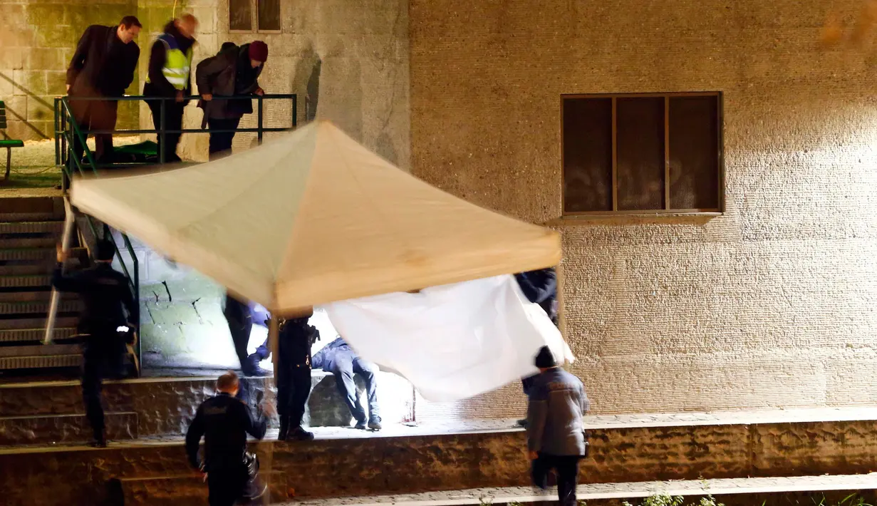 Sejumlah kepolisian menutupi tubuh korban setelah insiden penembakan di sebuah masjid di kota Zurich, Swiss, Senin (19/12). Pelaku yang diperkirakan seorang pria berusia 30 tahun, diyakini telah melarikan diri. (REUTERS/Arnd Wiegmann)