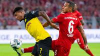 Gelandang Dortmund, Jadon Sancho, berebut bola dengan gelandang Bayern Munchen, Thiago Alcantara, pada laga Piala Super DFL di Stadion Signal Iduna, Dortmund, Sabtu (3/8). Dortmund menang 2-0 atas Munchen. (AFP/Ina Fassbender)