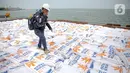 Pekerja berjalan melewati tumpukan karung beras saat melakukan aktivitas bongkar muat beras impor di Pelabuhan Tanjung Priok, Jakarta, Jumat (16/12/2022). Perum Bulog mendatangkan 5.000 ton beras impor asal Vietnam guna menambah cadangan beras pemerintah (CBP) yang akan digunakan untuk operasi pasar. (Liputan6.com/Faizal Fanani)