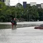 Warga melintas dekat sebuah mobil yang terendam banjir setelah Badai Harvey menghantam kota Houston, Texas, Minggu (27/8). Banjir bandang yang dibawa Badai Harvey telah membuat Houston, kota terbesar keempat di AS, semakin terisolasi (AP/David J. Phillip)