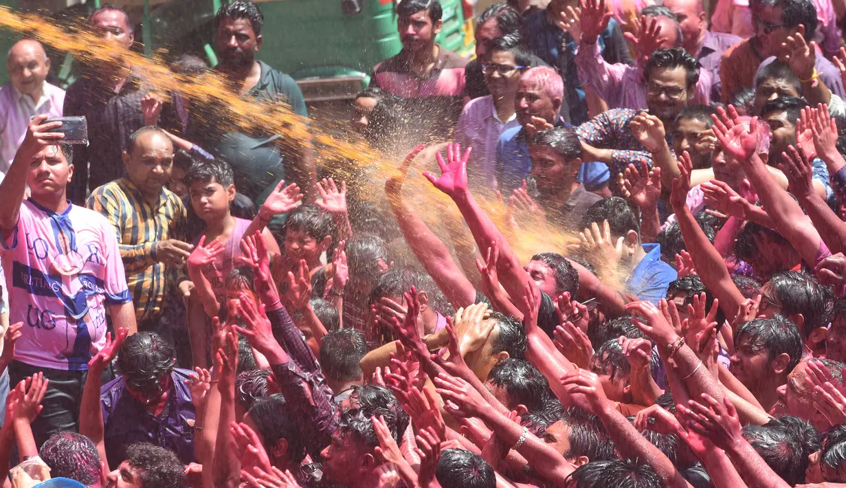 Umat Hindu India disemprot dengan cairan berwarna dalam festival keagamaan Holi di Kuil Swupramayan Kalupur, Ahmedabad, Rabu (20/3). Festival Holi atau yang dikenal dengan Festival Warna menjadi ajang untuk saling berbagi cinta. (SAM PANTHAKY / AFP)