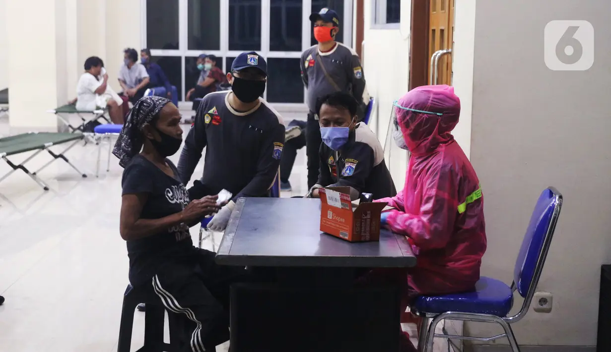 Petugas kesehatan melakukan pengecekan terhadap tunawisma di GOR Tanah Abang, Jakarta, Minggu (26/4/2020). Pemprov DKI Jakarta menyiapkan GOR di Jakarta untuk ditempati warga yang tidak mempunya tempat tinggal akibat terdampak Covid-19. (Liputan6.com/Angga Yuniar)