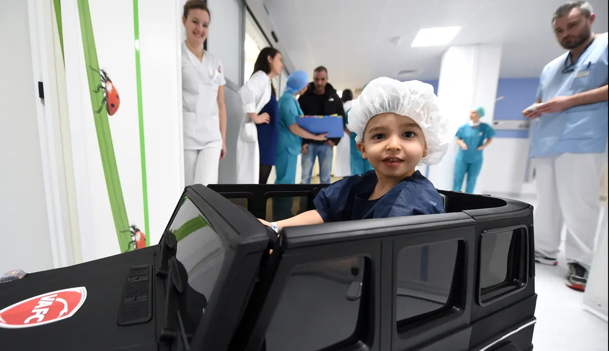 Petugas medis melihat Souvail (2) menggunakan mobil mainan listrik menuju ruang operasi di Rumah Sakit Valenciennes, Prancis, Jumat (2/2). Program ini untuk membuat anak-anak lebih santai sebelum menjalani prosedur operasi. (FRANCOIS LO PRESTI/AFP)