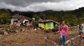 Warga berjalan melewati rumah-rumah yang rusak di sebuah desa yang terdampak banjir di Malalak, Sumatera Barat, Jumat 28 November 2025. Jelang akhir November 2025, bencana banjir bandang dan tanah longsor melanda sebagian besar wilayah pulau Sumatera. (AP Photo/Ade Yuandha)