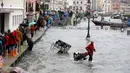 Warga berjalan melewati papan saat gelombang pasang menerjang Venesia, Italia, Selasa (12/11/2019). Venesia dilanda banjir akibat gelombang pasang setinggi 127 cm. (AP Photo/Luca Bruno)
