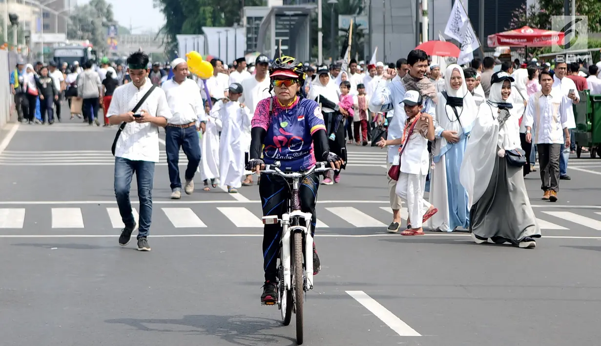 Seorang warga bersepeda di antara peserta Reuni 212 saat Car Free Day (CFD) di kawasan Jakarta, Minggu (2/12). Warga tetap memadati area Car Free Day  dari Bundaran HI-Sudirman meskipun ada aksi Reuni 212. (Liputan6.com/Angga Yuniar)