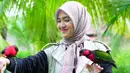 Cut Syifa terlihat manis mengenakan hijab dengan model yang dibentuk seperti pita di bagian depan. Dalam foto ini Cut Syifa berfoto bersama dua burung yang ia beri nama Kimmy dan Dido. (Instagram/@cutsyifaa)