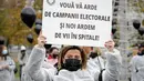 Para petugas medis yang mengenakan masker memegang balon hitam di Bucharest, Rumania, Selasa (17/11/2020). Aksi tersebut untuk mengenang pasien COVID-19 yang tewas dalam kebakaran di instalasi gawat darurat rumah sakit di Piatra Neamt, Rumania pada 14 November 2020 lalu. (AP Photo/Vadim Ghirda)