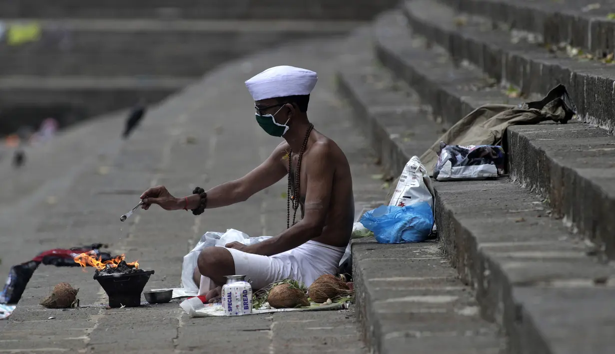 Umat Hindu mengenakan masker untuk mencegah terpapar virus corona COVID-19 saat melakukan ritual selama gerhana matahari di Banganga, Mumbai, India, Minggu (21/6/2020). Fenomena gerhana matahari pada 21 Juni 2020 terlihat dari berbagai negara di dunia. (AP Photo/Rajanish Kakade)