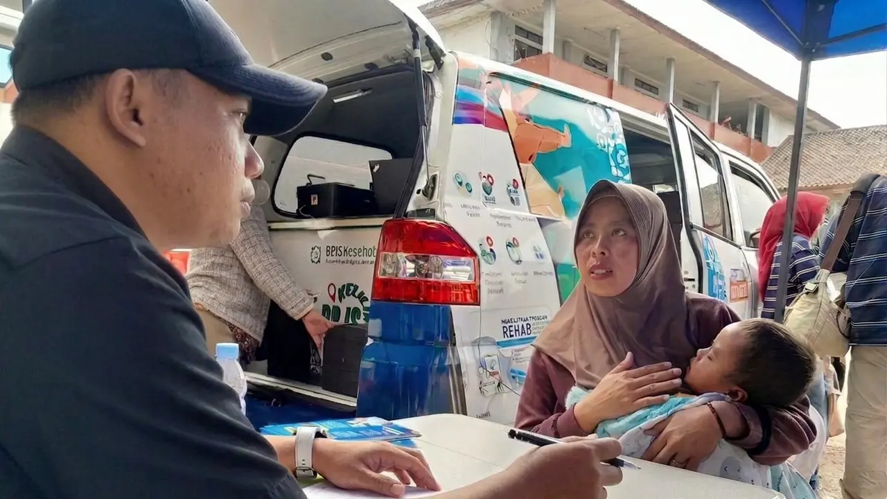 Seorang ibu asal Pangalengan, Kabupaten Bandung tengah mendaftar untuk menanyakan kepesertaan JKN buah hatinya kepada petugas BPJS Keliling.