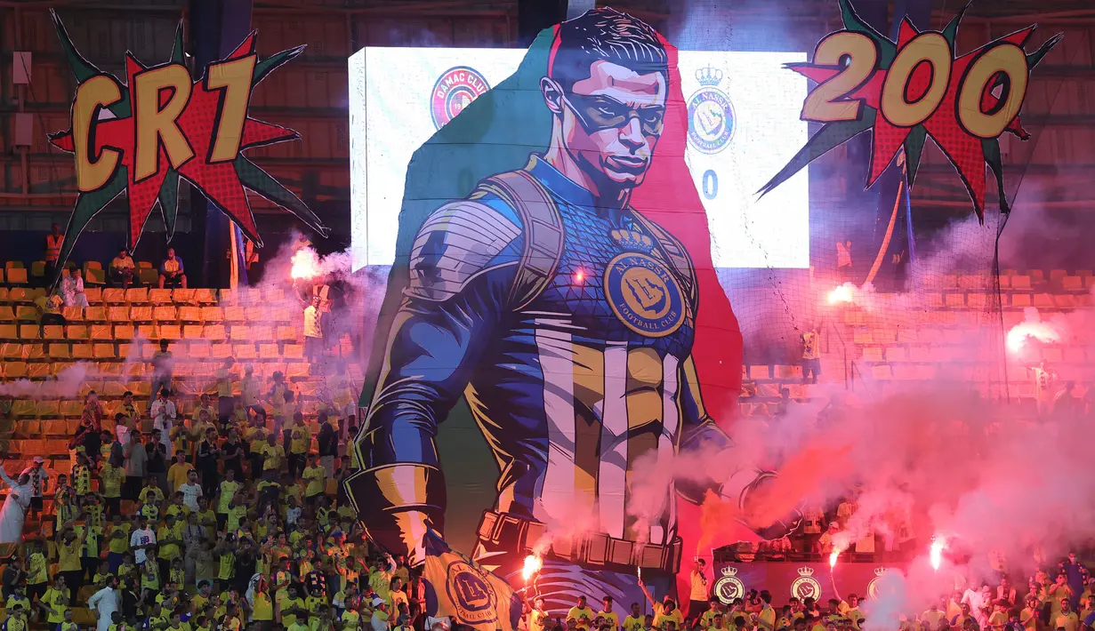 Para pendukung Al Nassr membentangkan poster bergambar superhero Captain Amerika berwajah Cristiano Ronaldo saat laga pekan ke-10 Liga Arab Saudi 2023/2024 antara Al Nassr menghadapi Damac di King Saud University Stadium, Riyadh, Sabtu (21/10/2023) malam WIB. (AFP/Fayez Nureldine)