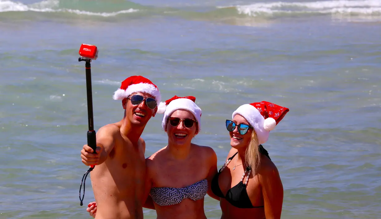 Para turis mengenakan topi natal berselfie saat merayakan hari Natal di Bondi Beach Sydney pada Hari Natal di Australia, (25/12). (REUTERS/David Gray)