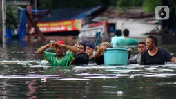 Warga melintasi banjir yang merendam perumahan Villa Mutiara Pluit, Tangerang, Banten, Senin (3/2/2020). Banjir disebabkan jebolnya tanggul sungai di sekitar kawasan tersebut. (merdeka.com/Magang/Muhammad Fayyadh)