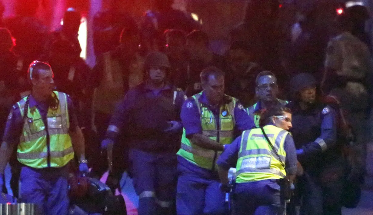 Polisi bersenjata lengkap membantu tim medis mengevakuasi para korban sandera yang terluka menjauh dari Kafe Lindt, Sydney (16/12/2014). Lebih dari 16 jam beberapa orang menjadi korban penyanderaan yang terjadi di Kafe Lindt. (REUTERS/David Gray)