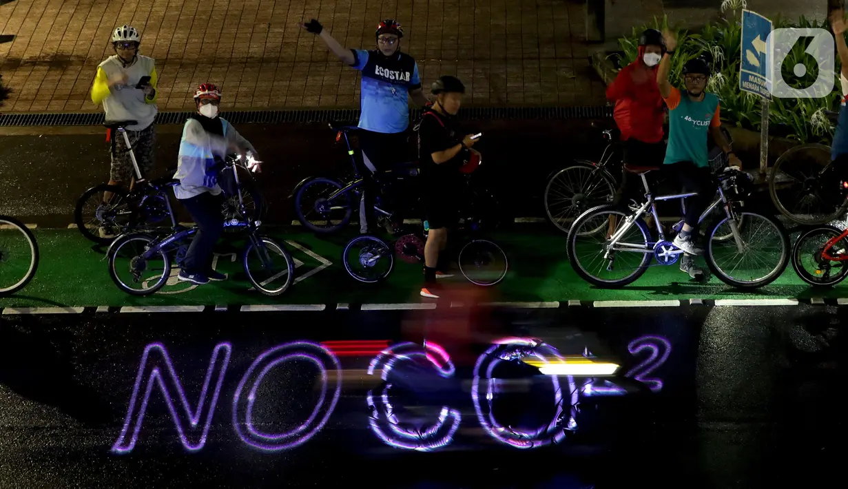 Pegiat bersepeda dan aktivis pecinta lingkungan saat aksi gowes Kelap Kelip Jakarta Night Ride #NOP26 di Jalan Jenderal Sudirman, Jakarta, Jumat (26/11/2021). Aksi ini mendorong pemimpin dunia berkomitmen meningkatkan tingkat bersepeda untuk mengurangi emisi karbon. (Liputan6.com/Helmi Fithriansyah)