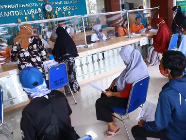 Warga antre menerima Bantuan Sosial Tunai (BST) di Kelurahan Pondok Benda, Kecamatan Pamulang, Tangerang Selatan, Minggu (10/01/2021). BST senilai Rp300 ribu akan disalurkan selama empat bulan berturut-turut mulai dari Januari - April 2021. (Liputan6.com/Fery Pradolo)