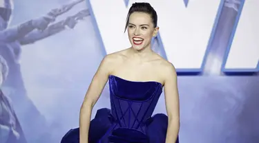 Aktris Inggris Daisy Ridley tertawa di karpet merah saat tiba menghadiri pemutaran perdana film Star Wars: The Rise Of Skywalker" di London (18/12/2019). Daisy Ridley tampil anggun dengan memancarkan kemewahan dalam balutan gaun navy ball straples. (AFP/Tolga Akmen)