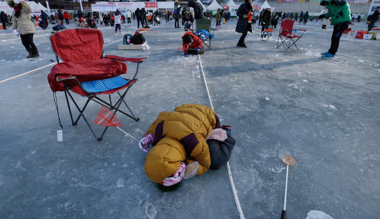 Peserta mengintip keadaan di bawah sungai saat acara Festival Es di sungai Hwacheon yang membeku di Korea Selatan, Sabtu (14/1). (AP Photo/Ahn Young-joon)