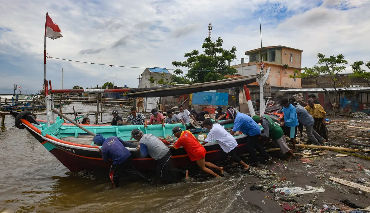Warga bergotong royong mendorong perahu nelayan ke perairan usai direkondisi di Kampung Nelayan Tanjung Pasir, Tangerang, Banten, Rabu (22/01/2025). (merdeka.com/Arie Basuki)