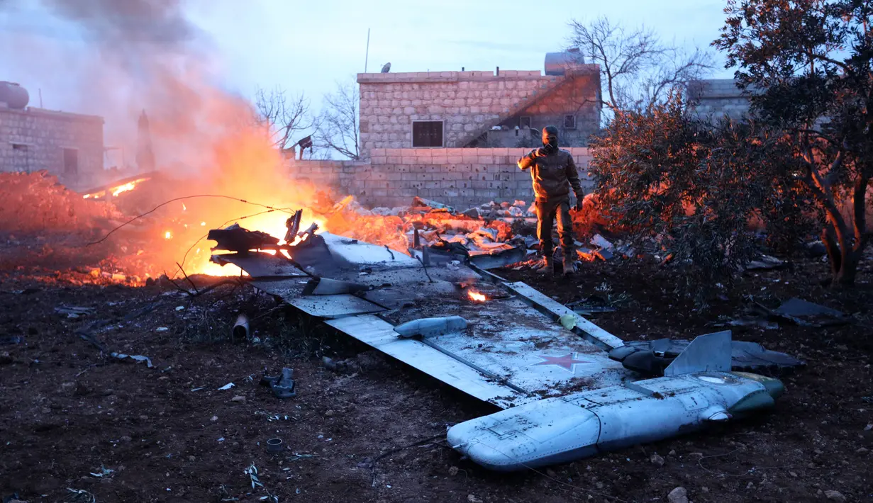 Seorang militan Suriah mengambil gambar jet tempur Sukhoi-25 milik Rusia yang jatuh di provinsi Idlib, Suriah (3/2). Menurut laporan lembaga Observasi HAM Suriah, jet tempur Rusia itu ditembak jatuh pada Sabtu sore. (AFP/Omar Haj Kadour)