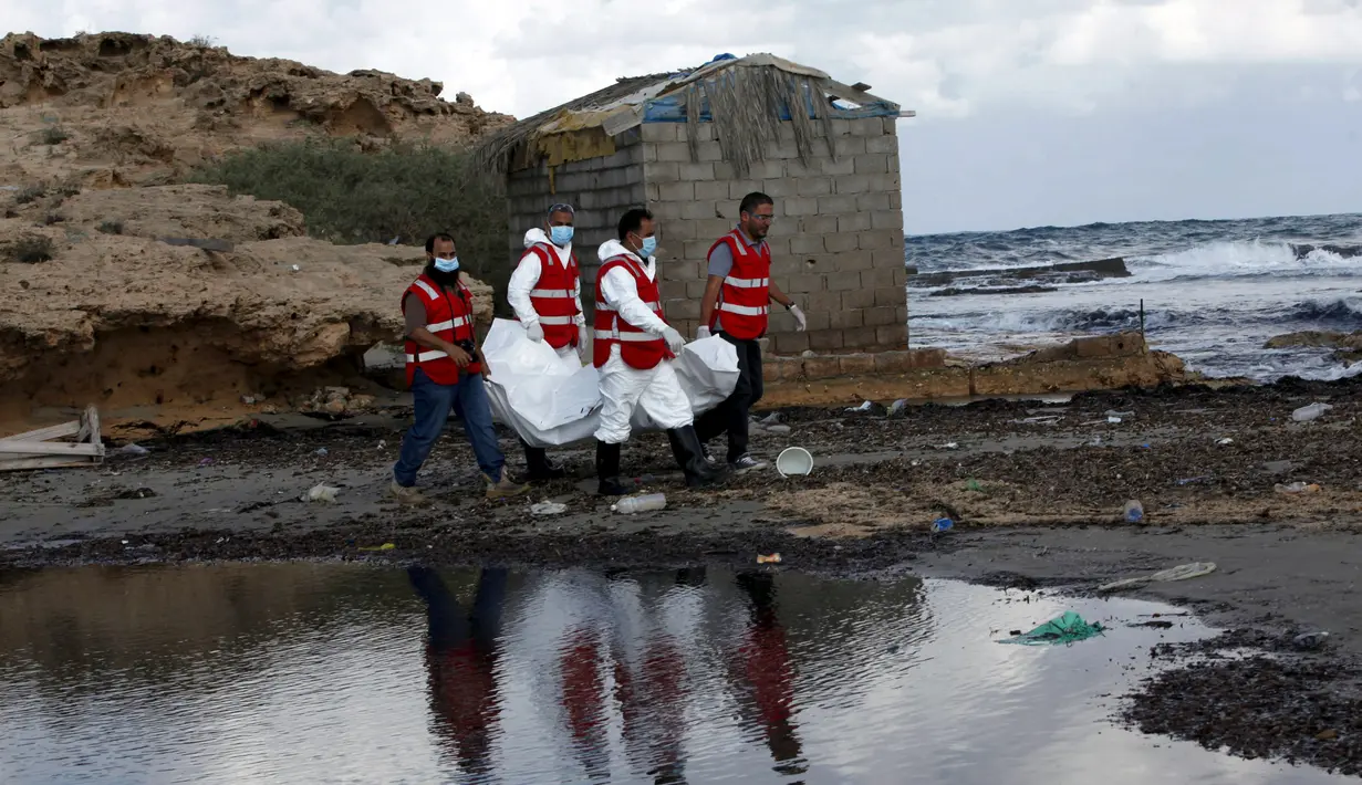 Kelompok Bulan Sabit Merah Libya menggotong kantong mayat berisi jenazah, diduga imigran yang tewas tenggelam di pantai Khoms, sebelah timur Tripoli, Minggu (25/10). Sedikitnya 40 jasad telah ditemukan di pantai Libya. (REUTERS/Ismail Zitouny)