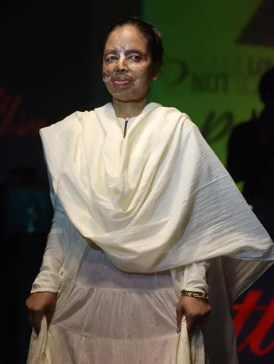Seorang wanita korban kekerasan dan penyiraman air keras mengenakan busana karya Anupanra berjalan diatas panggung saat peragaan busana di New Delhi, India (25/11). (AFP Photo/Dominique Faget)