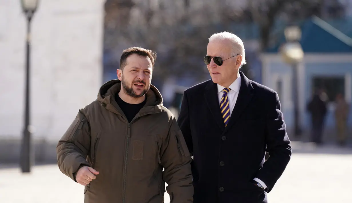 Presiden AS Joe Biden (kanan) berjalan di samping Presiden Ukraina Volodymyr Zelensky (kiri) saat tiba untuk kunjungan di Kyiv, Ukraina pada 20 Februari 2023. Presiden AS Joe Biden melakukan kunjungan mendadak ke Kyiv pada 20 Februari 2023, menjelang peringatan satu tahun invasi Rusia ke Ukraina. Biden bertemu dengan Presiden Ukraina Volodymyr Zelensky di ibu kota Ukraina dalam kunjungan pertamanya ke negara itu sejak dimulainya konflik. (Dimitar DILKOFF/AFP)