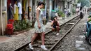 Gambar pada 21 Oktober 2018, turis berfoto di tengah jalur kereta api yang melintasi kawasan permukiman di Hanoi, 20 Oktober 2018. Beberapa tahun terakhir, pengunjung ke kawasan ini lebih menyukai mengambil kesempatan untuk fotografi. (Nhac NGUYEN/AFP)