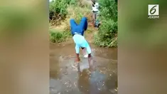 Agar sepatu mahalnya tak kotor, seorang pria memilih berjalan menggunakan tangan saat menyeberangi sungai.