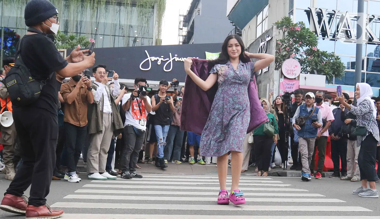 Artis Jessica Iskandar berlenggak-lenggok di zebra cross Dukuh Atas saat meramaikan Citayam Fashion Week di kawasan SCBD (Sudirman Citayam Bojong Gede Dukuh Atas), Dukuh Atas, Jakarta Pusat, Senin (25/7/2022). Jessica Iskandar tampak anggun mengenakan gaun bunga-bunga dengan luaran blazer bewarna ungu. (Liputan6.com/Herman Zakharia)