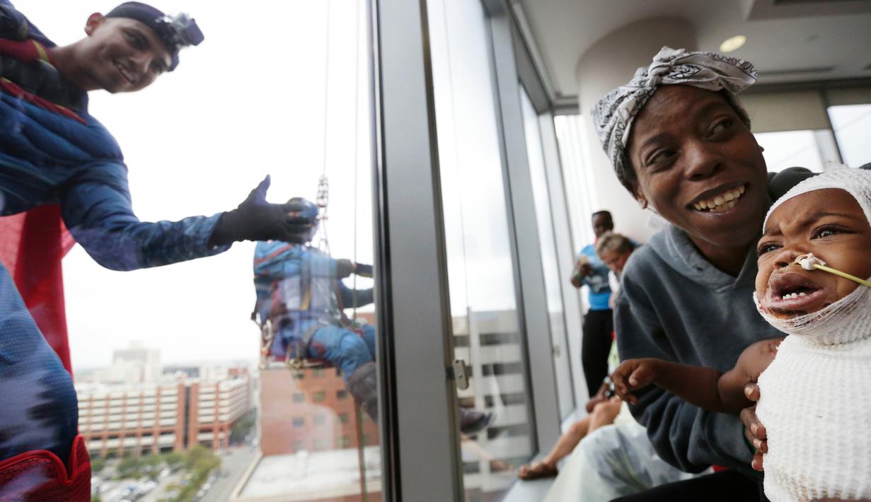Pasien anak bereaksi saat superhero Superman melambaikan tangan di jendela sebuah rumah sakit di Birmingham, Rabu (11/10). Sekelompok superhero bekerja membersihkan jendela rumah sakit untuk menghibur anak- anak yang sedang sakit (AP Photo/Brynn Anderson)