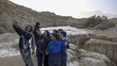 Anak-anak Israel berswafoto saat terjadi banjir bandang menyusul hujan lebat di gurun Negev di sebelah timur kota Dimona Israel pada 26 Desember 2022. Hujan lebat mengguyur Israel pada hari Senin (26/12) membanjiri jalan-jalan kota, memicu banjir bandang di dasar sungai gurun yang kering dan membasahi daerah pedesaan karena suhu turun ke level terendah musim ini. (AFP/Menahem Kahana)