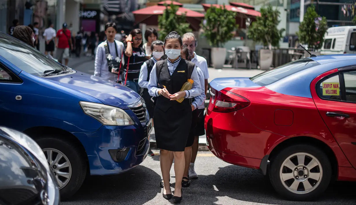 Pejalan kaki mengenakan masker di tengah kekhawatiran akan penyebaran virus corona COVID-19, di Kuala Lumpur, Malaysia, Kamis, (13/2/2020). Di Malaysia, ada 18 kasus virus Covid-19, sebanyak 12 kasus terjadi pada warga negara China, sedang enam lainnya warga lokal. (AFP/Mohd Rasfan)