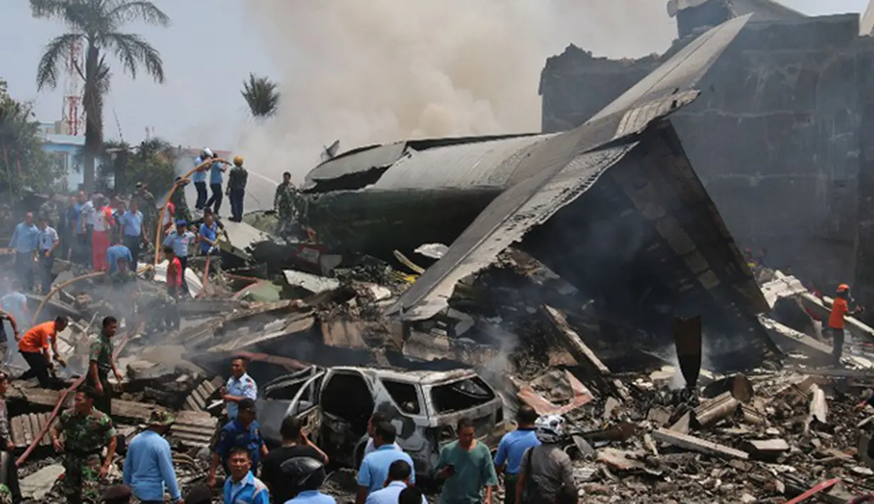 Sejumlah Petugas berusaha melakukan evakuasi pesawat Hercules C-130 yang jatuh di kawasan perumahan di Medan, Selasa (30/6/2015). Hercules C-130 milik TNI AU jatuh tidak lama setelah lepas landas. (AFP PHOTO/Kharisma Tarigan)