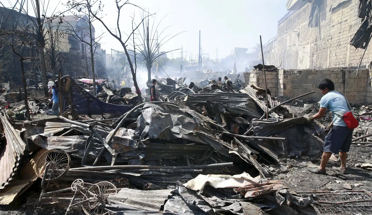 Sejumlah warga saat mencari barang - barang yang masih bisa digunakan di reruntuhan pasca kebakaran yang terjadi di kota Quezon, Filipina, Jumat (23/10/2015).  Sekitar 100 rumah habis terbakar dalam kejadian ini. (REUTERS/Romeo Ranoco)