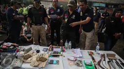 Petugas mengamati barang bukti yang berhasil didapat pada penggerebekan di Kampung Bahari, Tanjung Priok, Jakarta, Kamis (25/8). Pelaksanaan penggrebekan dilakukan di 8 titik berbeda yang sudah dipetakan Polres Jakarta Utara. (Liputan6.com/Faizal Fanani)