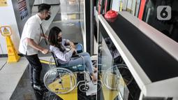 Petugas Light Rail Transit (LRT) Jakarta membantu penumpang disabilitas dengan kursi roda menaiki rangkaian gerbong kereta di Stasiun Pegangsaan Dua, Jakarta Utara, Selasa (24/1/2023). LRT Jakarta dilengkapi dengan berbagai fasilitas untuk para penumpang seperti Kesehatan dan Nursery room, Pos Sahabat Perempuan dan Anak (SAPA), bangku prioritas untuk penyandang disabilitas, orang tua, ibu hamil, dan anak-anak. (merdeka.com/Iqbal S. Nugroho)