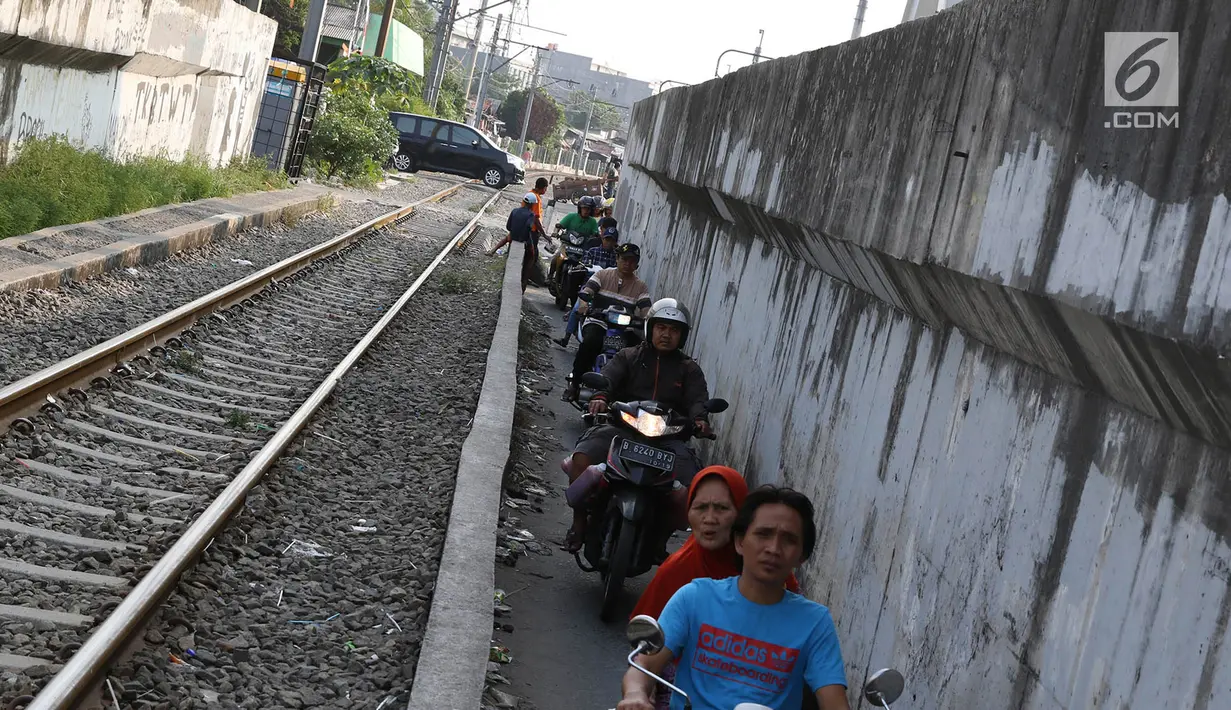 Pengendara sepeda motor melintasi jalan setapak di pinggir rel kereta di kawasan Tambora, Jakarta, Senin (10/7). Tidak tersedianya akses jalan untuk putar balik membuat warga terpaksa memanfaatkan jalan setapak tersebut. (Liputan6.com/Immanuel Antonius)