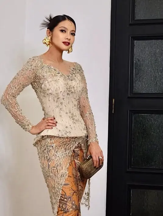 Rini Yulianti mengenakan kebaya berpayet coklat dari Maison Baaz Couture dipadukan bawahan kain coklat. Sambil membawa clutch coklatnya. [@riniyulianti]
