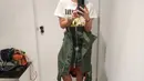 Ibu dua anak ini juga tampil santai dengan kaos putih dipadukan rok hijau asimetris dan sepatu hitamnya.  [@therealdisastr]