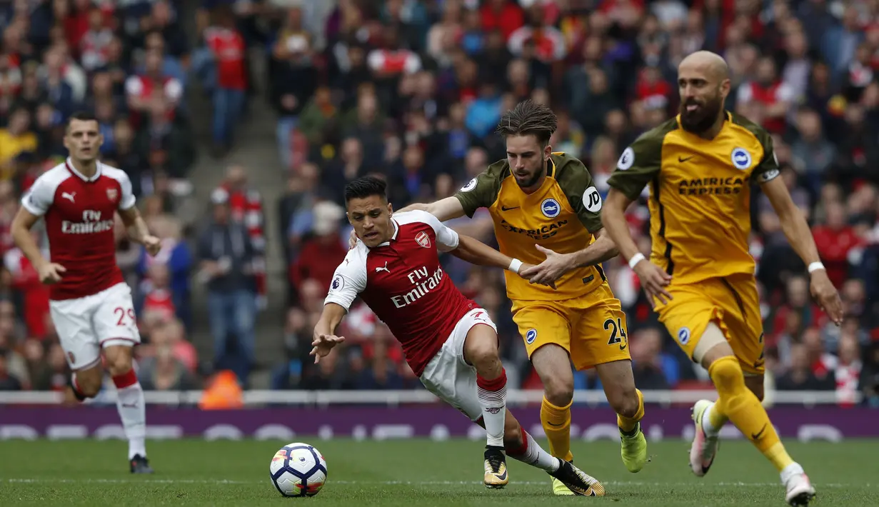 Pemain Arsenal, Alexis Sanchez (kiri) berusaha menjauh dari kejaran pemain Brighton pada lanjutan Premier League di Emirates Stadium, London, (1/10/2017). Arsenal menang 2-0. (AFP/Adrian Dennis) 