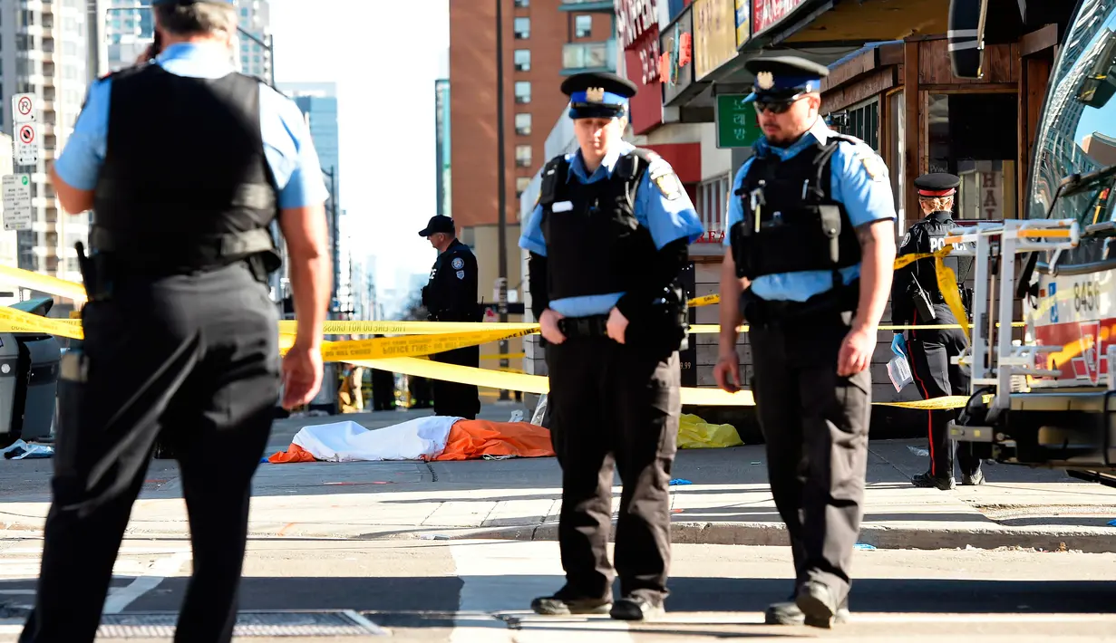 Petugas mengamankan area sekitar jasad yang tergeletak setelah sebuah van setelah menabrak para pejalan kaki di pinggiran utara Toronto, Kanada, Senin (23/4) Polisi telah menahan mobil boks warna putih dan sopir. (Nathan Denette/The Canadian Press via AP)