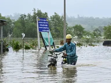 Seorang pria mendorong sepedanya melewati jalanan yang tergenang air di kota Hpa Yar Gyi di wilayah Bago, Myanmar, pada tanggal 9 Oktober 2023. (SAI AUNG MAIN/AFP)