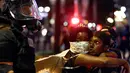 Dua orang pendemo menatap polisi yang berjaga di lokasi unjuk rasa di daerah Charlotte, North Carolina, AS, Rabu (21/9). Pengunjuk rasa protes atas penembakan pria kulit hitam oleh polisi. (REUTERS/Jason Miczek)