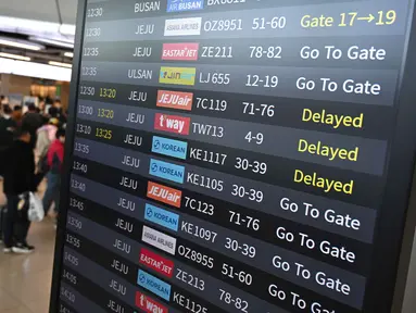 Penumpang berjalan melewati papan informasi yang menampilkan penerbangan tertunda di Bandara Gimpo, Seoul, pada Kamis 13 November 2025, pada hari ujian masuk perguruan tinggi tahunan yang dikenal secara lokal sebagai Suneung. (Jung Yeon-je/AFP)