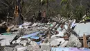 Seorang pria berjalan di tengah puing-puing rumah yang rusak akibat Badai Melissa di desa Boca de Dos Rios, provinsi Santiago de Cuba, Kuba pada Kamis 30 Oktober 2025. Sehari sebelumnya, atau Selasa (28/10/2025), badai ini menghantam Jamaika sebagai badai Kategori 5 yang sangat kuat. (YAMIL LAGE/AFP)