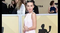 Millie Bobby Brown berpose di karpet merah Screen Actors Guild (SAG) Awards di Los Angeles, Minggu (21/1). Penampilan Millie menjadi tak biasa saat memilih mengenakan sneakers putih Converse daripada sepatu high heels. (Frazer Harrison/GETTY IMAGES/AFP)