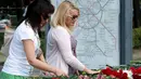 Beberapa wanita meletakkan karangan bunga di pintu masuk Stasiun Park Pobedy, lokasi tergelincirnya kereta bawah tanah, Moskow, (16/7/2014). (AFP PHOTO/Dmitry Serebryakov)