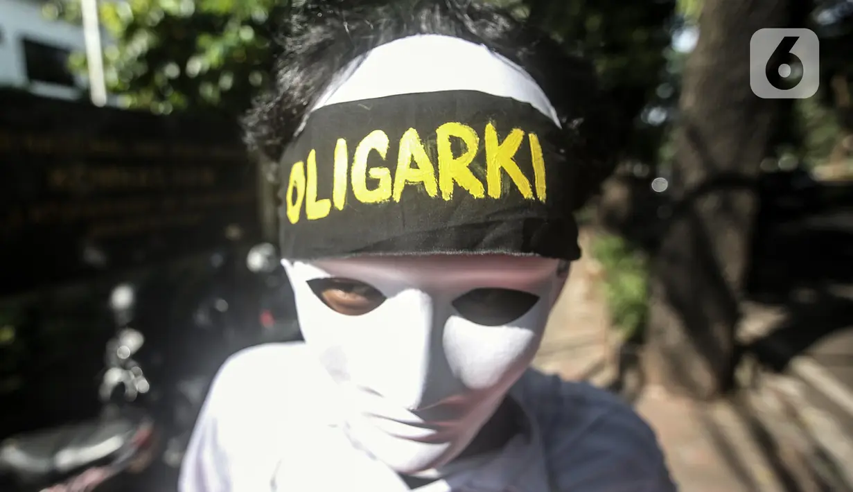 Seorang anak muda yang mengenakan topeng dan ikat kepala bertuliskan "Oligarki" menggelar aksi damai di luar Kantor Komnas HAM, Jakarta, Kamis (14/7/2022). Mereka meminta hak asasi akibat krisis iklim dengan mengadukan kepada Komnas HAM terkait pembiaran krisis Iklim karena sudah sangat berpengaruh pada kehidupan, ekonomi, dan kesehatan perorangan maupun kelompok akibat kenaikan suhu bumi serta cuaca ekstrem. (Liputan6.com/Faizal Fanani)